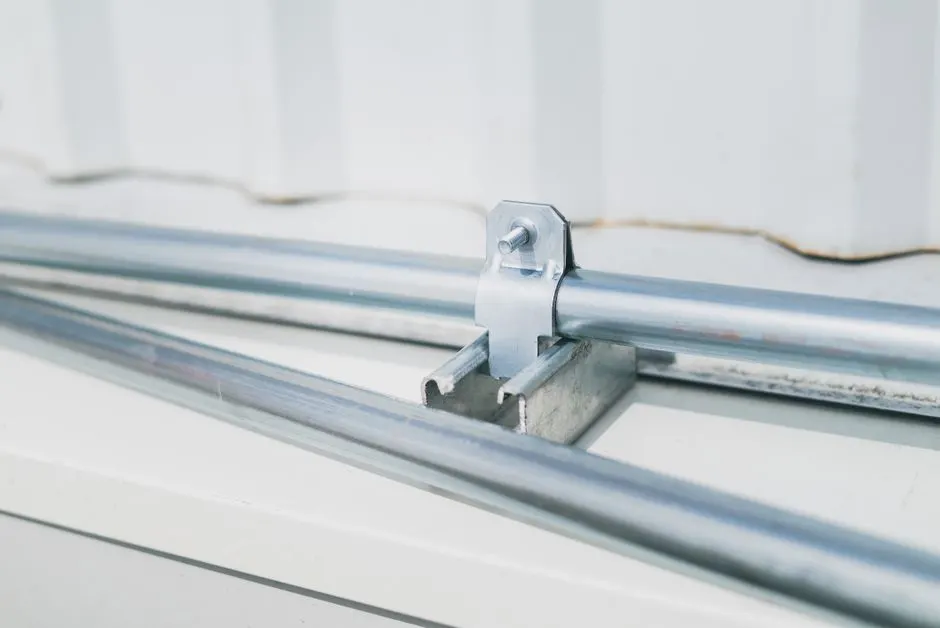 Detailed close-up of a metal pipe clamp on a stainless steel surface, highlighting industrial design.